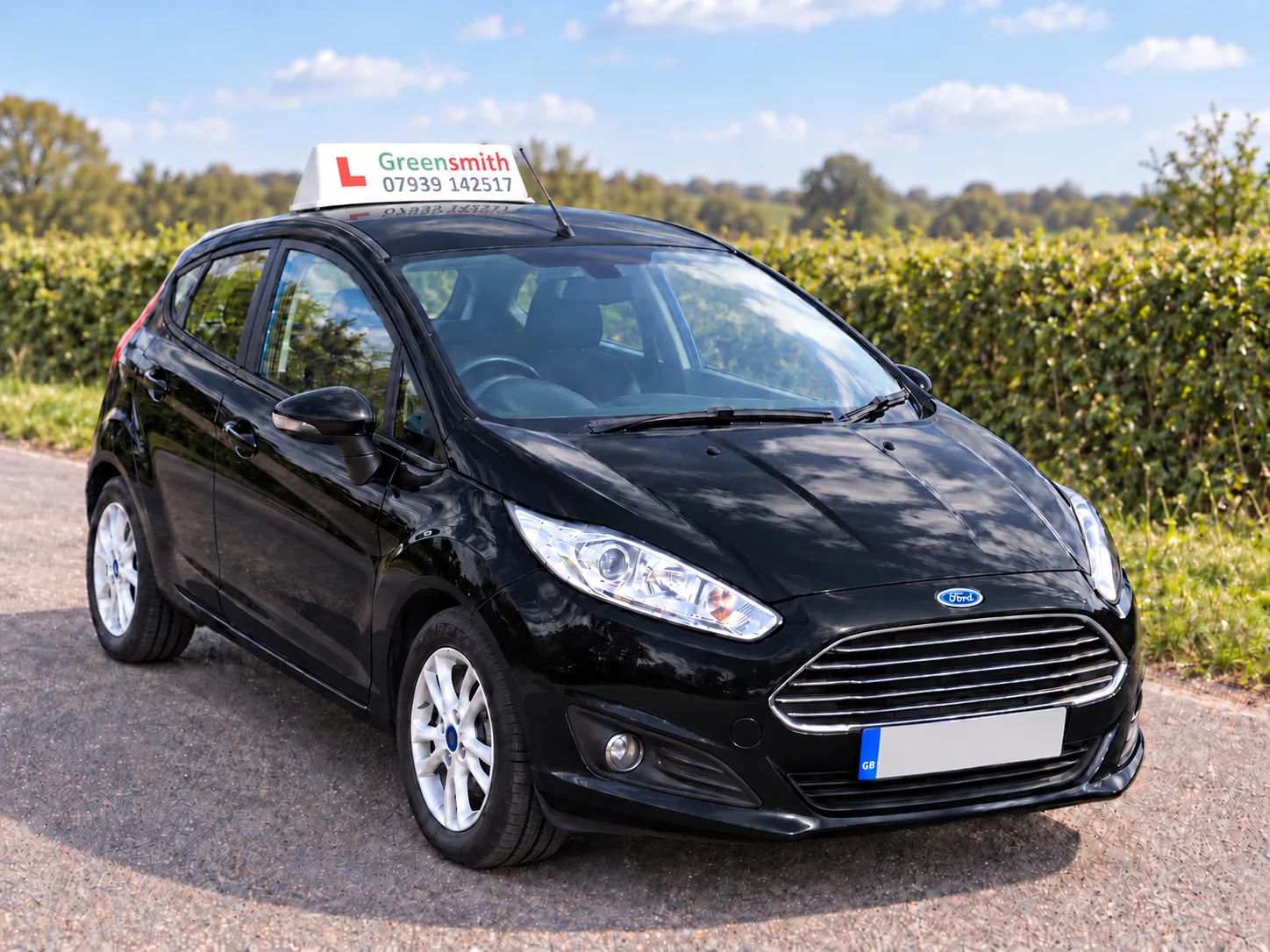 Rob’s black Ford Fiesta with a Greensmith learner sign, parked beside a quiet country hedge.